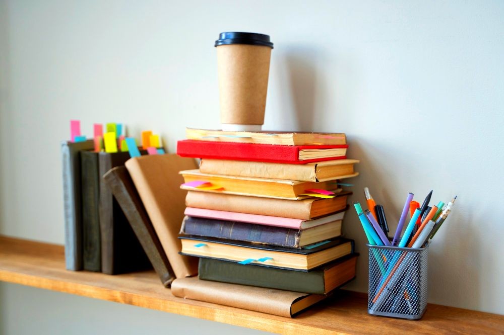 Photograph of a wooden shelf installed on a wall, with office items such as books and pens placed on it.